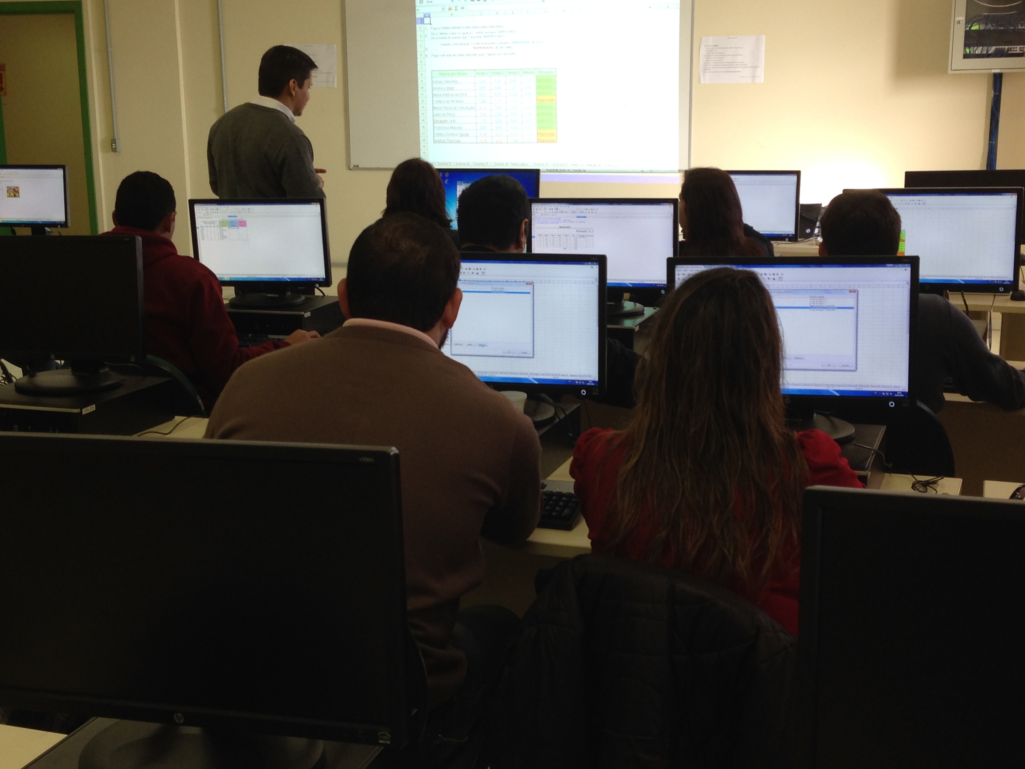 Servidores tiraram dúvidas sobre o uso do programa / Foto: Murilo Dotto Alunos acompanham explicação de planilha eletrônica em seus monitores de computador, enquanto instrutor, ao fundo da imagem, expõe o conteúdo em projeção sobre tela branca