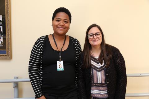 A estudante Manuela Rubim foi ao evento acompanhada da tradutora e intérprete de Libras da Unipampa, Taise Gomes dos Santos (Foto: Milene Marchezan) Parede bege. Duas mulheres. A primeira, da esquerda para direita, negra, cabelo curto, sorrindo; a segunda mais baixa, branca.