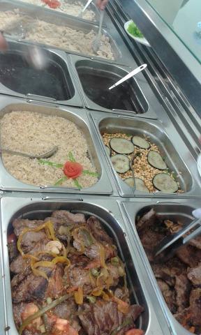 Foto: Daniela La Bella para ACS Unipampa linha de servir do restaurante universitário com alimentos já prontos para consumo; na frente, carne, arroz e feijão, e talheres para servir.